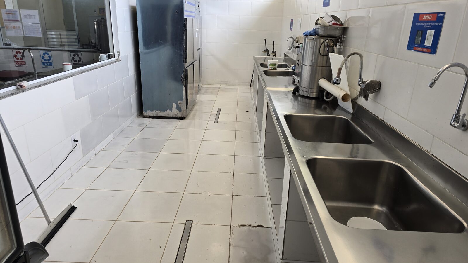 Cozinha industrial reformada com coifa central em inox sobre fogão de grande porte, paredes azulejadas e bancadas de granito