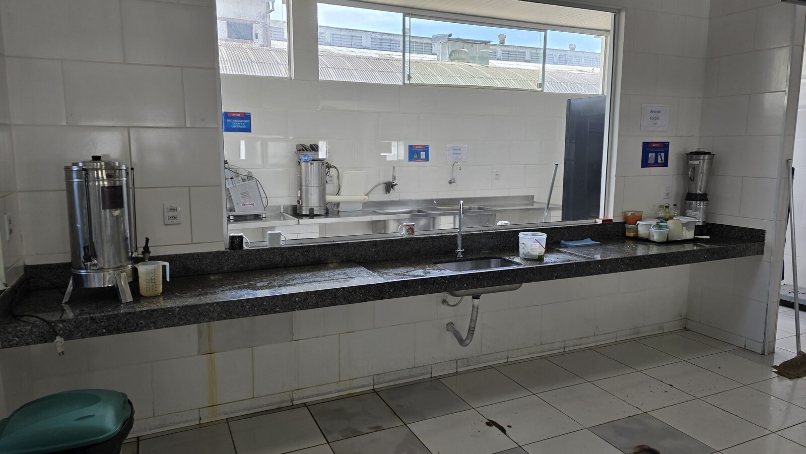 Área de preparo de carnes com cubas e bancadas em aço inox, processador de alimentos e sinalização de uso obrigatório de EPIs