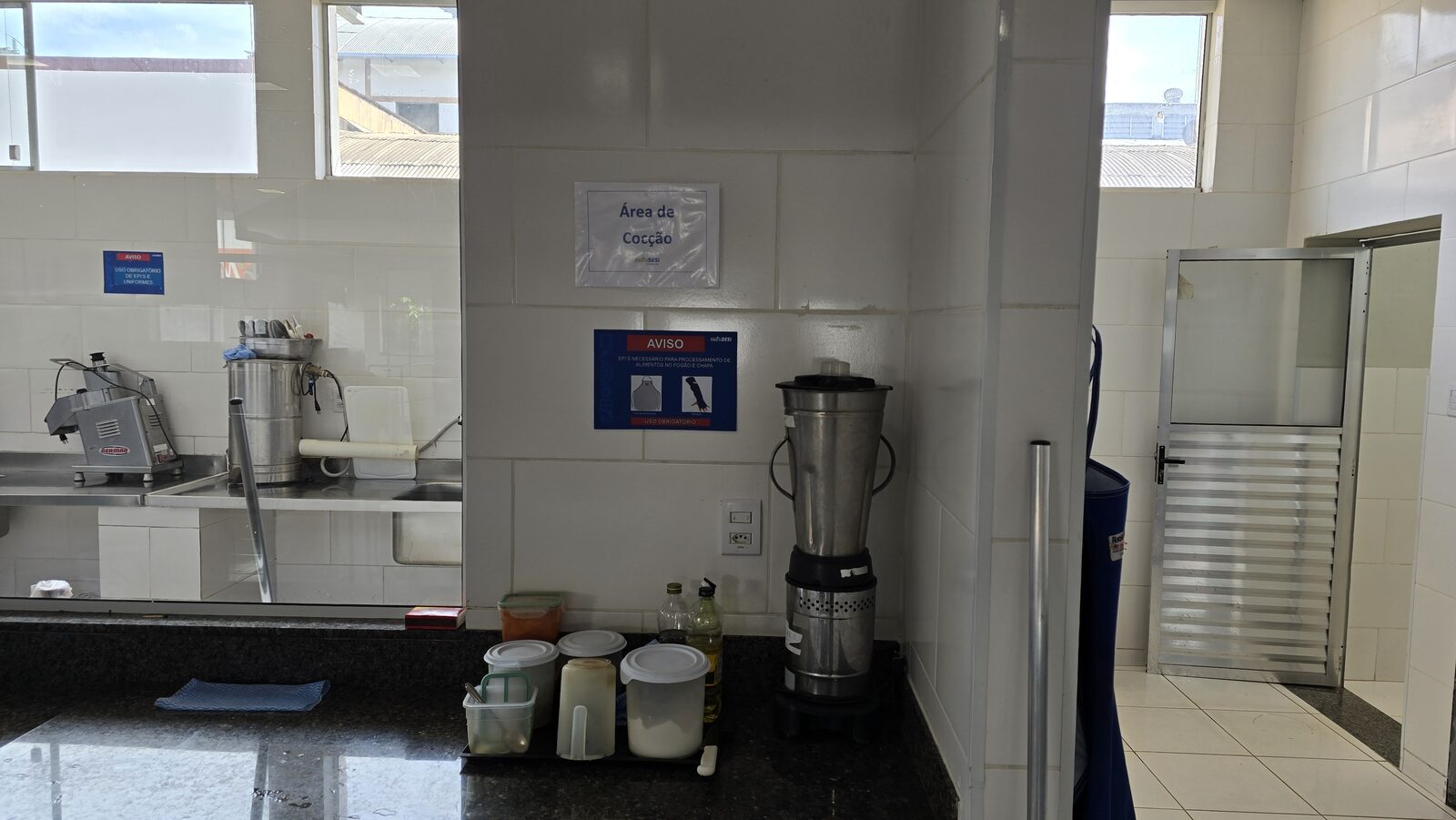 Guichê de devolução de bandejas e pratos com prateleiras de granito, separando o salão de refeições da área de higienização